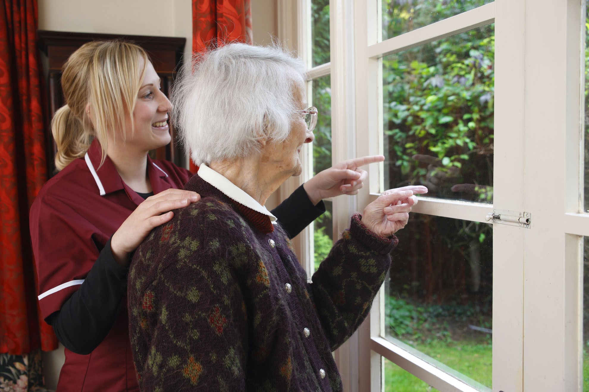 carer and her elderly pacient looking out of the window